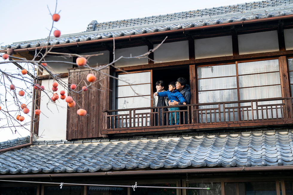 家族で2階の窓から外を見ている写真